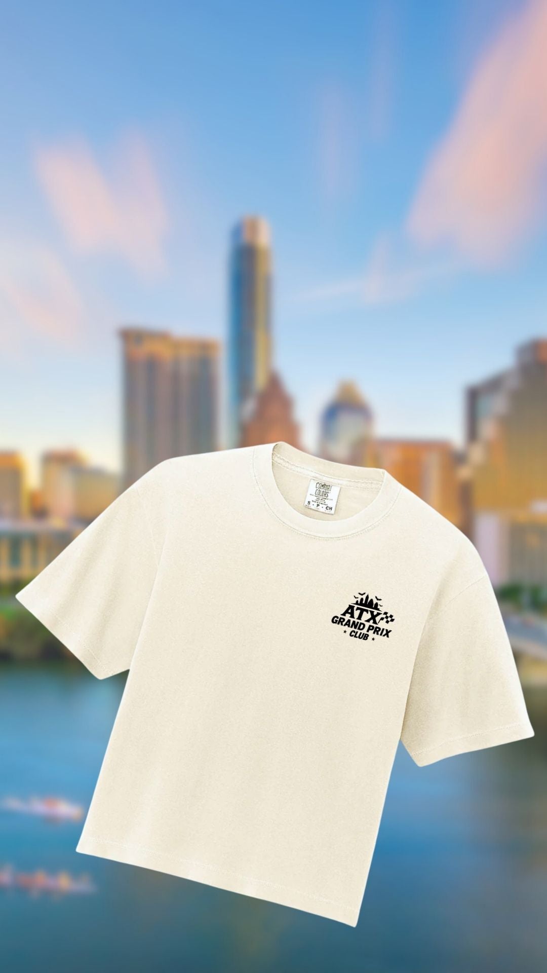 White t-shirt with a logo on a blurred Austin background